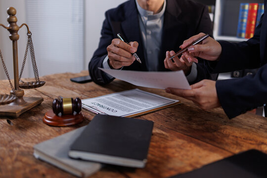 Lawyers counseling clients at an office table, discussing legal contract details, reviewing paperwork, and offering professional advice on law and justice