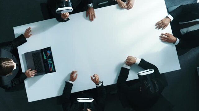 Top down aerial view of professional business team wear vr headset to enter virtual world while sitting and using hand gestures to manipulate the data from the manager laptop. Technology. Directorate.