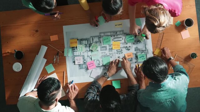 Top view of civil engineer writing and planning by using sticky notes to brainstorm idea. Top down aerial view of business people taking a note at table with project plans and equipments. Symposium.