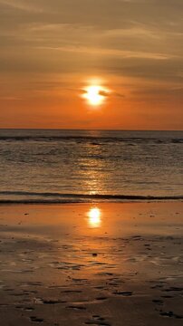 Golden sunset reflecting on wet beach and calm ocean