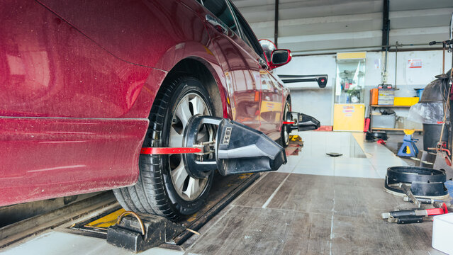 Car on 3D wheel alignment machine in a workshop garage.