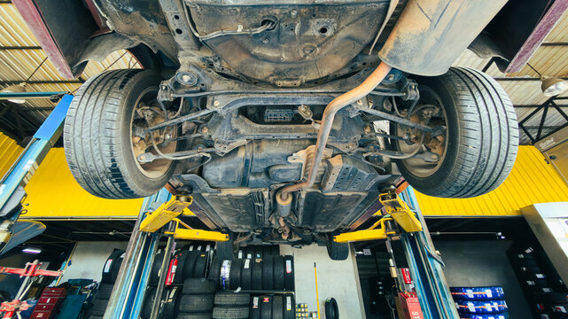 Car suspension and undercarriage system maintenance in repair shop.
