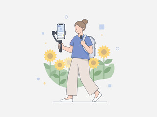 Fototapeta premium Young woman vlogging with smartphone gimbal and backpack while walking through sunflowers with happy mood