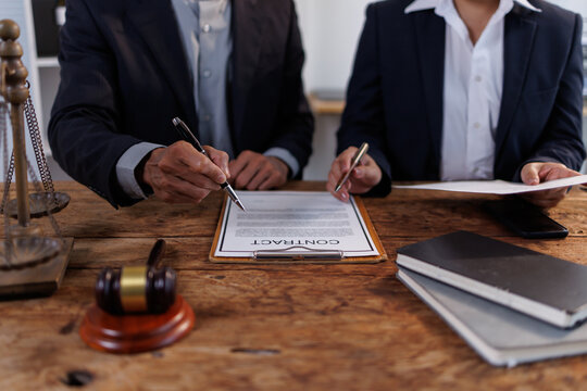 Lawyers explaining the legal implications of a formal document to a client. Guiding through crucial clauses before signing a significant contract. Symbolizing agreement. Compliance