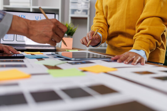 Ux designers engaging in a collaborative planning session. Reviewing app interface designs. Implementing mobile user experience principles. Tablet. And sticky notes