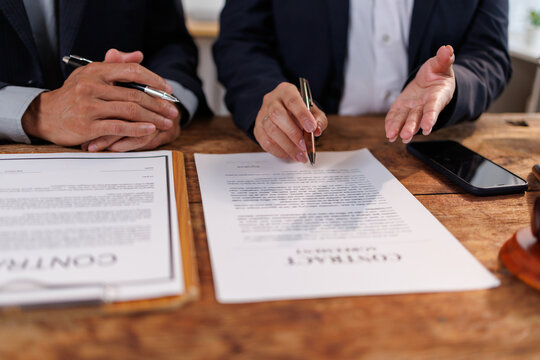 Legal professionals or business partners engaging in an important discussion. Reviewing documents. And preparing to sign a strategic agreement at a desk