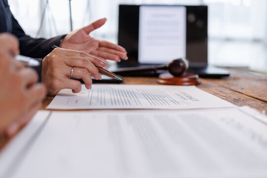 Professionals engaging in legal discussions. With hands pointing and holding a pen over a contract document. Signifying consultation. Negotiation