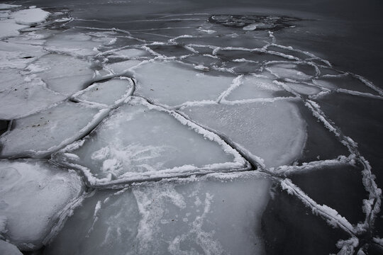 Abstract texture of broken ice floes on the sea surface. Natural geometric patterns of frozen water in winter, Nordic coastal landscape.
