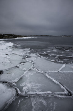 Abstract texture of broken ice floes on the sea surface. Natural geometric patterns of frozen water in winter, Nordic coastal landscape.