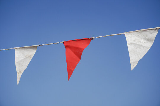 Red And White Pennant Bunting Flags Against Clear Blue Sky For Outdoor Party And Celebration