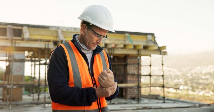 Engineer, man and wrist pain on construction site with injury, building accident and risk strain. PPE, mature person and hurt hand or fatigue with civil engineering error, sprain and overworked