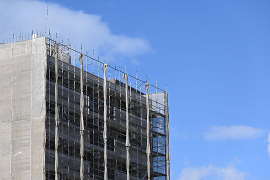 青空を背景に建つ建築中の高層ビル