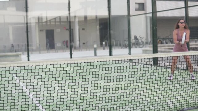 Beautiful woman learning to do remates at the net in a game of padel tennis