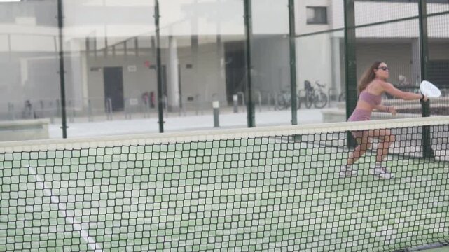 Woman returning the ball with a forehand shot during an outdoor padel training session