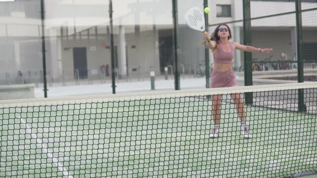 Female padel player hitting the ball with a forehand during a practice session on an outdoor court