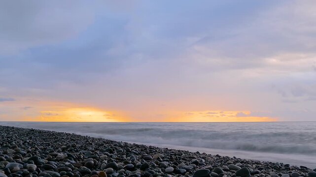 Timelapse - stormy water waves of the Black Sea are crashing on the pebble beach, coast. Fast moving clouds over the sea: nobody, no people. Nature, element, seascape, landscape and time lapse concept