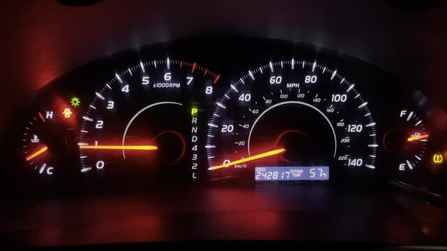 Modern vehicle dashboard showing engine performance and warning lights at night.