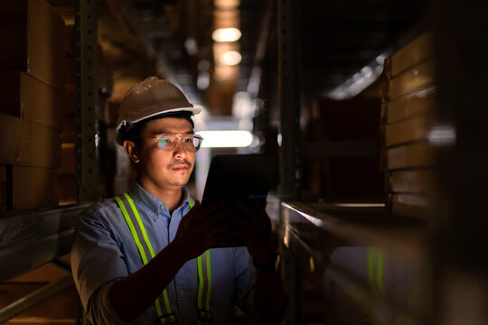 An Asian warehouse worker uses a digital tablet while working the night shift at a large warehouse.
Overtime work, night shift, warehousing industry, import-export.