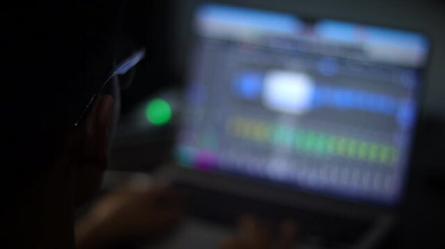Music Producer Editing Audio Project on Laptop in Creative Workspace