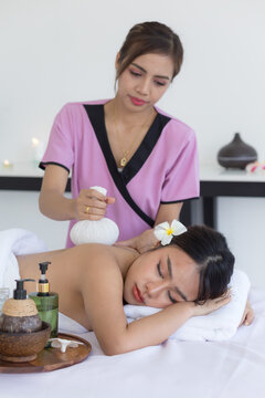 Asian woman enjoying a relaxing spa massage while lying on a massage table with eyes closed. Professional therapist providing wellness treatment in a luxury spa with massage oil,