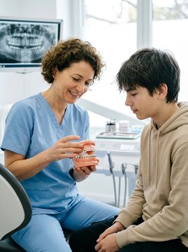Dentist explaining orthodontic braces treatment with dental model. For oral healthcare, patient education, orthodontic treatment planning, and preventive dentistry