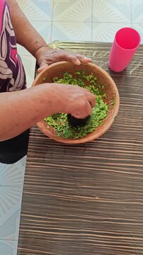 Woman Grinding Guaje Seeds with Pestle in Stone Molcajete