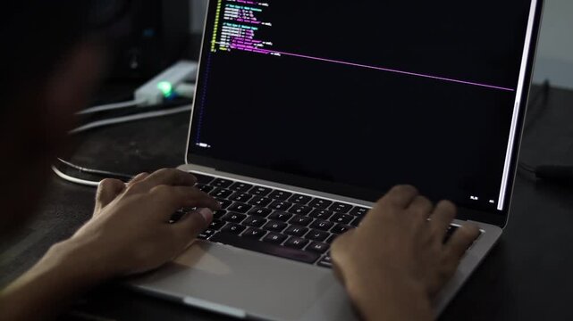Programmer Typing Source Code on Laptop Computer in Modern Workspace