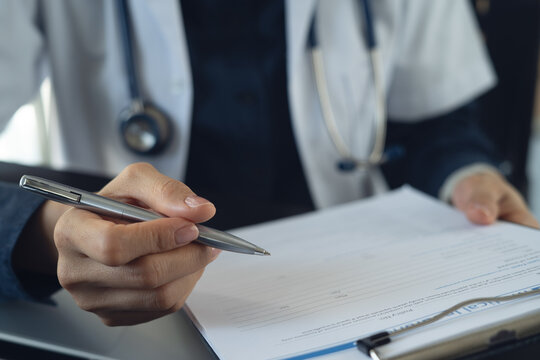 Close up of female doctor writing notes on clipboard, history record or healthcare checklist, medication document or insurance claim form in hospital office