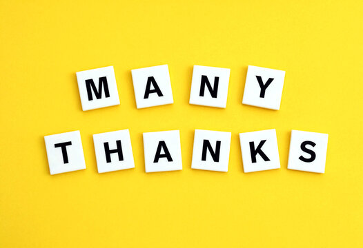 Bright yellow background with white scrabble tiles spelling many thanks in creative arrangement