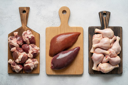 Raw chicken organ meats on wooden boards with liver hearts and gizzards for recipe preparation