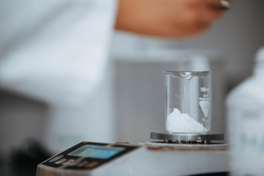 Laboratory Scientist Measuring White Powder in Beaker on Precision Scale During Experiment