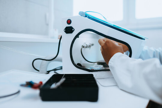 Dental Technician Working in Laboratory Polishing Dental Prosthesis Inside Protective Box