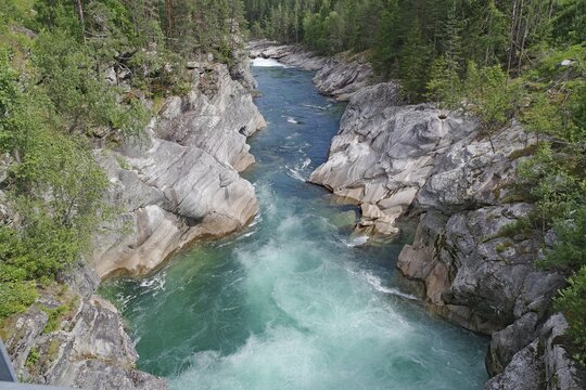 A turquoise river flows through a rocky gorge surrounded by green forests, rafting, Sjoa, Vinstra, Norway