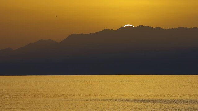 Sunset over sea surface with mountain silhouette in background, Matala, South Coast, Crete, Greek Islands, Greece