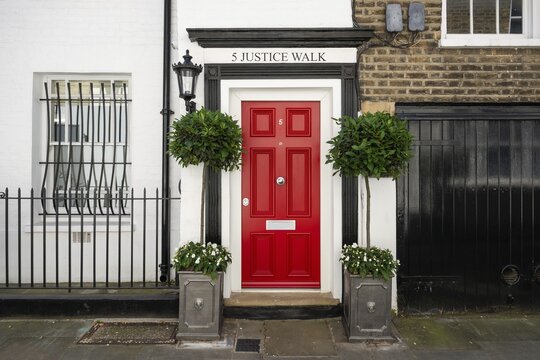 Red door with black edging, plants in pots and decorative lantern, white house facade, 5 Justice Walk, Chelsea, London, Great Britain, England, Great Britain