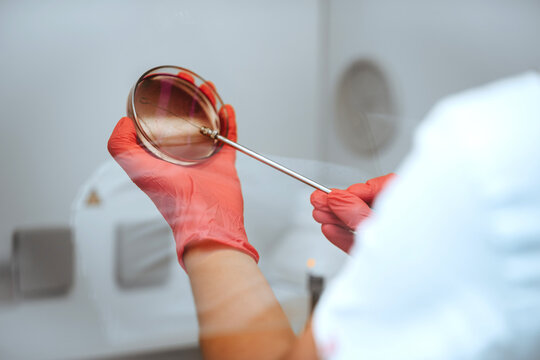 Laboratory Technician Sterilizing Inoculating Loop Over Flame While Holding Petri Dish Lid With Gloved Hands