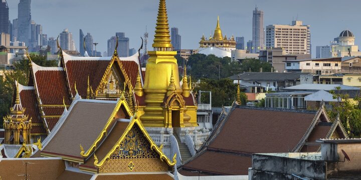 Wat Tri Thotsathep Worawihan with the Chedi glowing in the evening sun, Golden Mount behind it and the skyline of Bangkok, Thailand