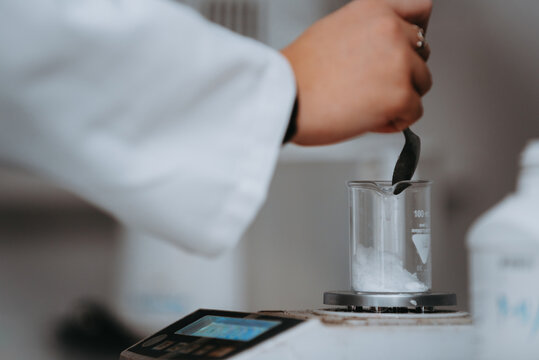 Scientist Stirring Powder in Beaker on Scale in Laboratory During Chemical Measurement and Experimentation