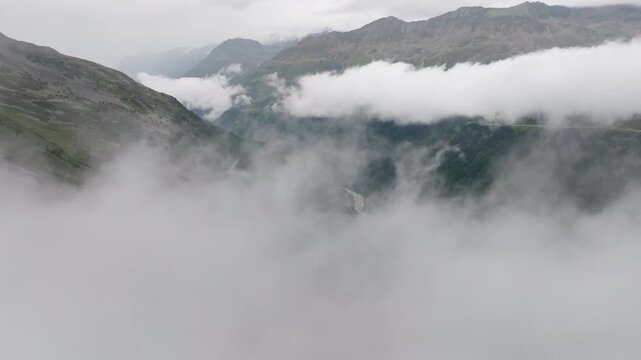 Drone aerial footage of Tyrol Alps with towering mountain peaks above clouds scenic rocky landscapes lush fields pristine wilderness and unforgettable European travel destination