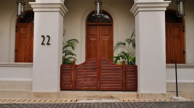 Symmetrical front view of an elegant colonial-style white building entrance with wooden doors, a louvred wooden gate, and house number 22.