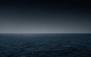 Fototapeta premium A calm dark sea meets a gradient dark sky at the distant horizon, showing a quiet seascape with gentle waves.