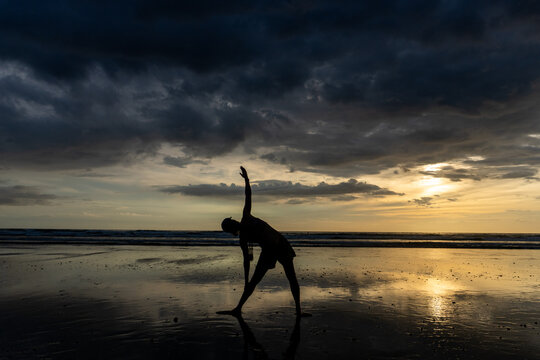 Person doing yoga silhouette on a beach at sunset