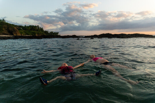 Woman and child peacefully floating in the ocean at dusk