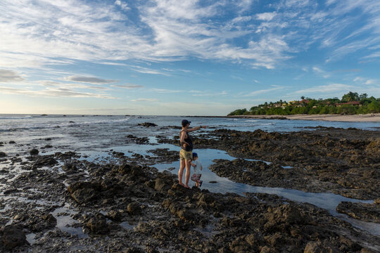 Mother and child exploring rocky beach tide pools