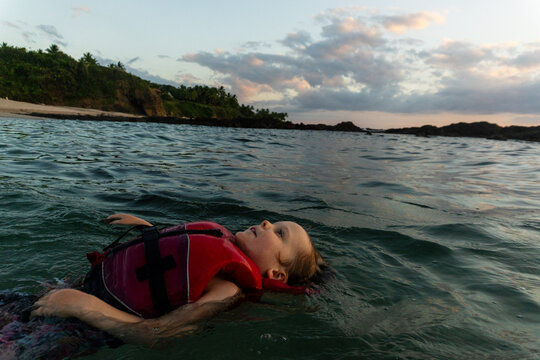 Young child floating peacefully in the ocean at dusk