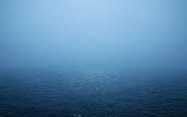 Fototapeta premium A tranquil seascape shows a vast deep blue ocean under a pale hazy sky, with gentle sparkles on the calm water surface.