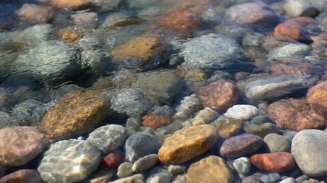 River stones in clear flowing water video. Colorful pebbles underwater in a shallow stream or creek bed. Natural scenic footage for environment and relaxation backgrounds.