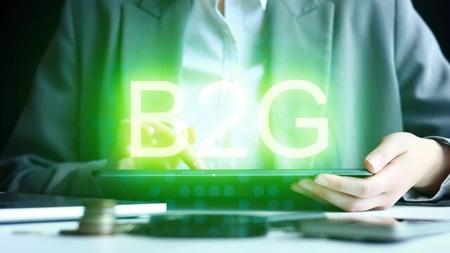 A business person is holding a tablet in a dark office. The screen shows large green letters that say B2G. Coins and papers are scattered on the table. The mood is focused and serious.