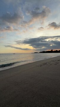 Tranquil tropical beach sunset with dramatic clouds and calm ocean waves