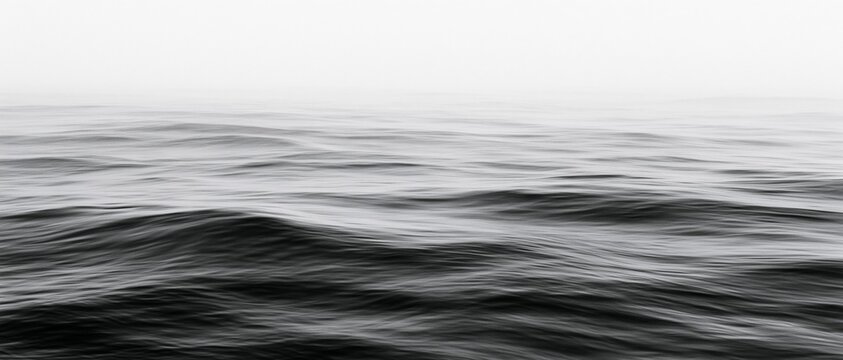 Monochrome ocean waves beneath a pale misty horizon